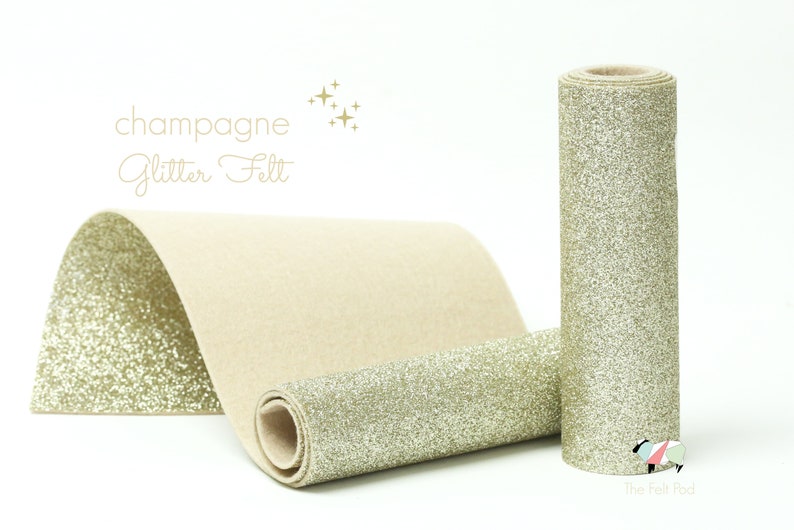 Puede incluir: Un rollo de fieltro de purpurina color champ&aacute;n. El fieltro es de color dorado claro con un acabado brillante. El rollo est&aacute; sobre una superficie blanca.