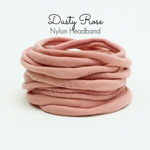 May include: A close-up of a pile of dusty rose nylon headbands. The headbands are soft and stretchy, perfect for babies and toddlers.