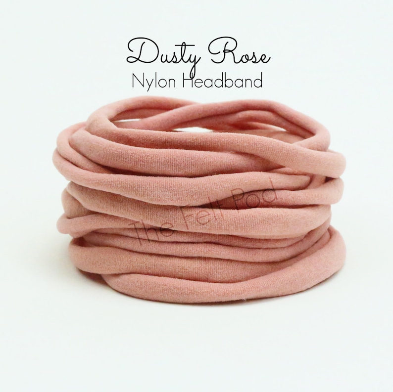 May include: A close-up of a pile of dusty rose nylon headbands. The headbands are soft and stretchy, perfect for babies and toddlers.