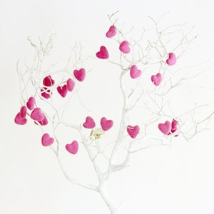 Puede incluir: Un &aacute;rbol de ramas blancas con corazones de fieltro rosa colgando de las ramas. Los corazones est&aacute;n dispuestos en un patr&oacute;n aleatorio.