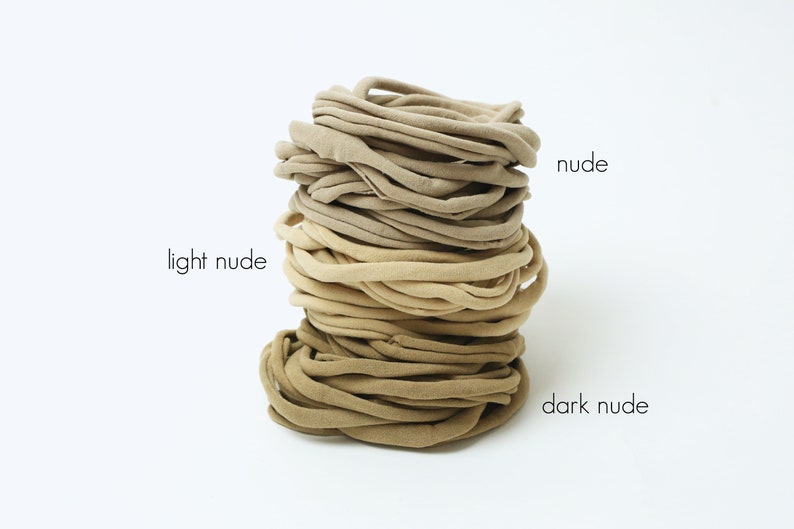 May include: A stack of nude hair ties in three shades: light nude, nude, and dark nude.