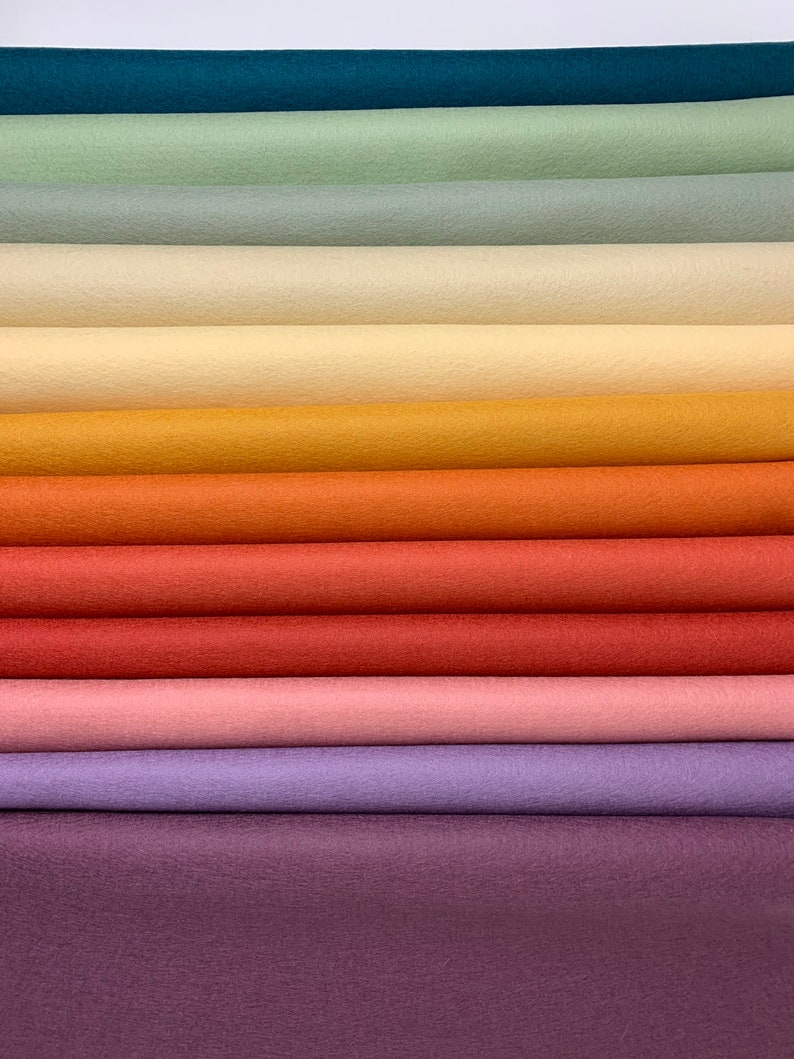 Puede incluir: Una pila de diez muestras de tela de fieltro en varios tonos de azul, verde, amarillo, naranja, rojo, rosa, morado y marr&oacute;n.