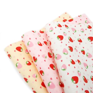 Peut inclure: Trois échantillons de tissu avec un motif répété de fraises rouges et de cœurs blancs sur un fond rose, rose clair et blanc.