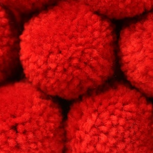 May include: Close-up of a group of red pom-poms. The pom-poms are soft and fluffy, and they are arranged in a random pattern.