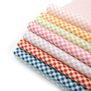 Op de afbeelding: Een stapel van acht stofstalen in verschillende kleuren met een ruitpatroon. De kleuren omvatten blauw, rood, oranje, groen, roze en paars.