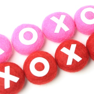 May include: Pink and red felt balls with white letters spelling out "XOXO" on each ball.