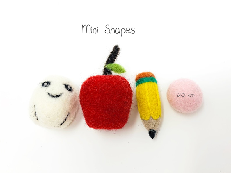 May include: Mini felt shapes, including a red apple, a yellow pencil, a white ball with a smiley face, and a pink ball. The text "Mini Shapes" is above the shapes. The pink ball has the text "2.5 cm" on it.