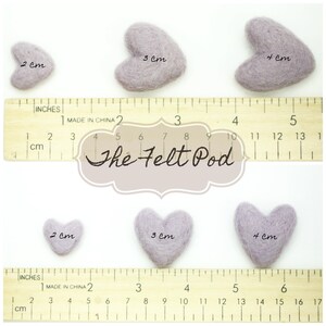 May include: Three felt heart shapes in different sizes, 2 cm, 3 cm, and 4 cm, with a ruler for reference. The felt hearts are a light purple color. The image includes the text "The Felt Pod".