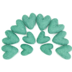 Puede incluir: Un semic&iacute;rculo de corazones de fieltro color turquesa dispuestos en fila. Los corazones son todos del mismo tama&ntilde;o y forma.