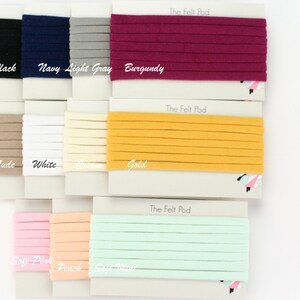 May include: A variety of nylon headbands in different colors, including black, navy, light gray, burgundy, nude, white, cream, gold, soft pink, peach, and soft mint. The headbands are displayed on white cards with the text "The Felt Pod" printed on them. The text "NYLON HEADBANDS" is printed on the right side of the image.