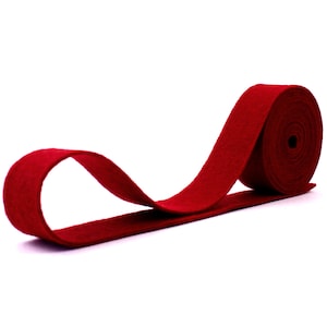 May include: A roll of red felt ribbon. The ribbon is approximately 1 inch wide and is rolled up neatly.