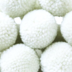 May include: A group of white fluffy pom poms, arranged in a pyramid shape.