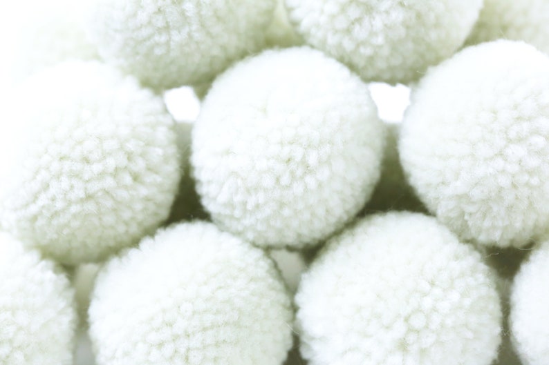 May include: A group of white fluffy pom poms, arranged in a pyramid shape.