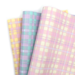 May include: Three pieces of fabric with a plaid pattern in pastel colors. The fabric on the left is yellow and pink, the middle fabric is light blue and purple, and the fabric on the right is pink and white.