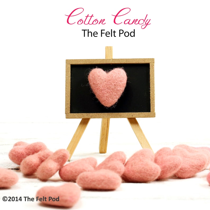 May include: A pink felt heart on a small chalkboard easel with the text "Cotton Candy The Felt Pod".  Pink felt hearts are scattered on a white wooden surface.