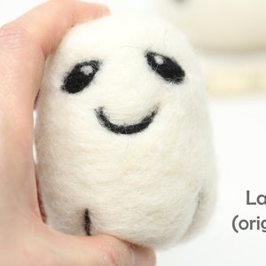 May include: White felt ghost with black eyes and a smiling mouth. The ghost is being held in a hand. The text "Large (original)" is visible in the bottom right corner of the image.