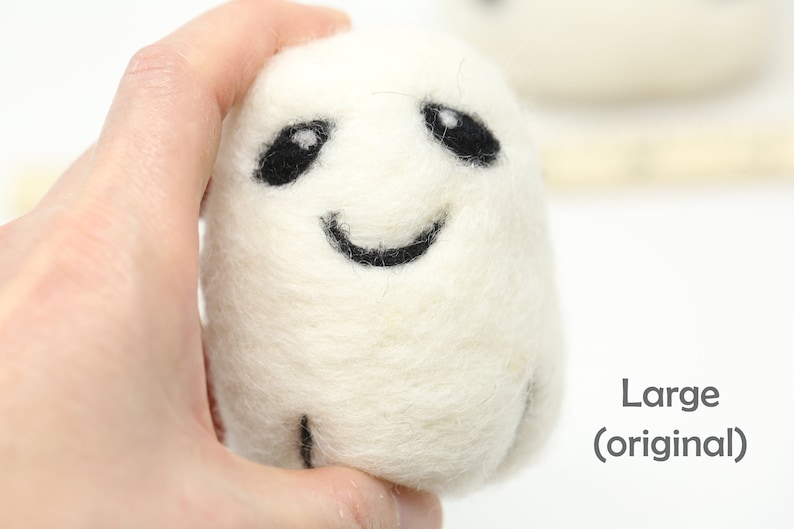 May include: White felt ghost with black eyes and a smiling mouth. The ghost is being held in a hand. The text "Large (original)" is visible in the bottom right corner of the image.