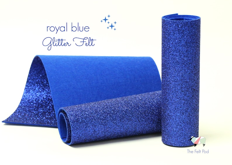 Puede incluir: Fieltro azul real con purpurina, enrollado y presentado sobre una superficie blanca. El fieltro es de un azul intenso con un acabado brillante.