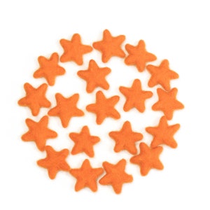 May include: A circle of orange felt star shapes on a white background.