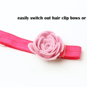 May include: A pink elastic headband with a pink felt flower attached. The headband is designed to easily switch out hair clip bows or flowers.