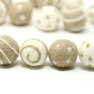 Peut inclure: Six boules en feutre beige et blanc avec différents motifs. Les boules présentent une variété de motifs, notamment des rayures, des spirales et des pois.