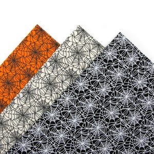 May include: Three fabric swatches with a spiderweb pattern. The swatches are orange, off-white, and black, each with a white spiderweb design. The fabric is likely for Halloween-themed crafts or decor.