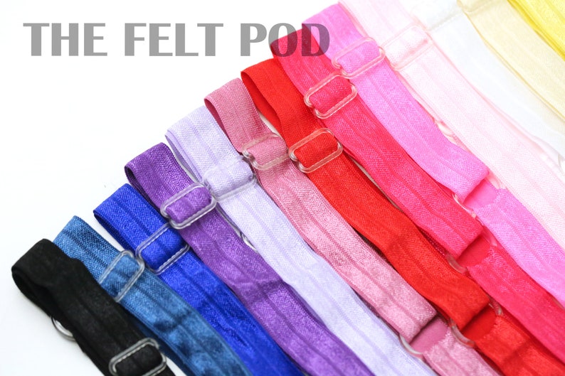 May include: A set of 10 colorful elastic hair ties with adjustable plastic buckles. The hair ties are arranged in a rainbow pattern, starting with black and ending with yellow.