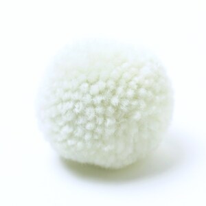 May include: A white fluffy pom pom, a round ball of yarn, perfect for crafting projects.