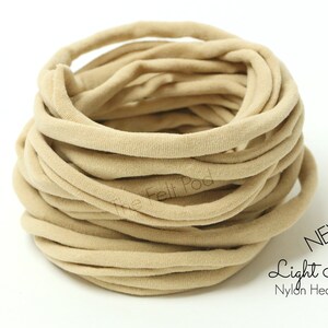 May include: A close-up of a large spool of light nude nylon headband material. The material is soft and stretchy, and it is perfect for making headbands, hair ties, and other accessories. NEW Light Nude Nylon Headband.