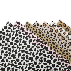 Peut inclure: Une collection d'échantillons de tissu avec des motifs animaliers. Les motifs comprennent des taches de vache noires et blanches, des taches de vache roses et des imprimés léopard de différentes couleurs. Les tissus sont disposés en éventail, mettant en valeur les différents motifs.