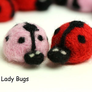 May include: Two felt ladybugs, one red and one pink, with black spots and antennae. The ladybugs are handmade and have a fuzzy texture.