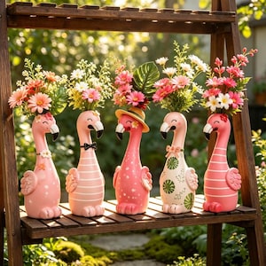 May include: Five pink flamingo-shaped planters arranged in a row, each holding a unique bouquet of artificial flowers. The flamingos feature varied patterns, including stripes, polka dots, and leaf motifs, with some wearing accessories like hats or bows.