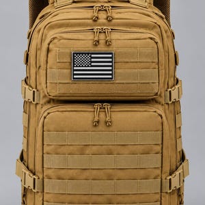 May include: A tan tactical backpack featuring multiple zippered compartments, adjustable side compression straps with buckles, and a rectangular patch displaying a black and white American flag graphic on the upper front pocket.