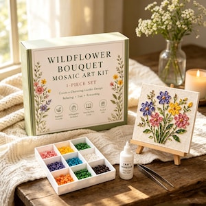 Op de afbeelding: Een Wildflower Bouquet mozaïekkunstset, een afgewerkt bloemenmozaïek op een houten ezel, een wit dienblad met negen vakjes voor kleurrijke mozaïektegels, een flesje knutsellijm en een metalen pincet voor een creatief project.