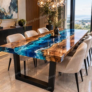 Könnte beinhalten: Ein rechteckiger Esstisch mit einer Massivholzplatte mit Naturkante und einem zentralen Flussdesign aus glänzendem blau-weißem Epoxidharz. Der Tisch steht auf zwei schwarzen, U-förmigen Metallbeinen und ist von sechs beigen Polsterstühlen umgeben.
