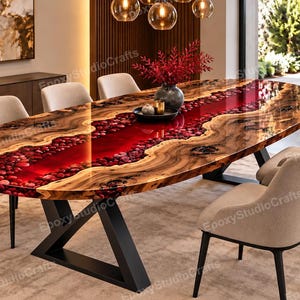 May include: An oval dining table featuring a live edge wood slab with a central river design filled with glossy red resin and embedded red stones. The table is supported by a black metal Z-shaped base and surrounded by six beige upholstered chairs.