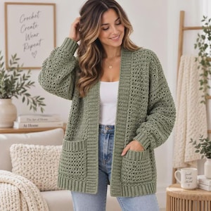 May include: An olive green open-front cardigan featuring a chunky crochet knit pattern, long sleeves with ribbed cuffs, and two large front patch pockets. The garment is worn over a plain white top and light blue denim jeans, showcasing a textured design.