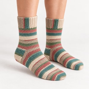 May include: A pair of mid-calf length socks featuring a horizontal striped pattern in muted tones of beige, sage green, and dusty rose. The socks are constructed with a visible crochet stitch, including a ribbed cuff and a reinforced heel section.