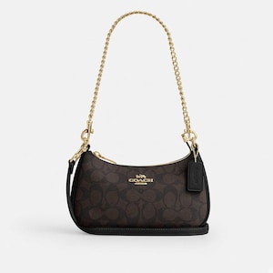 Könnte beinhalten: Eine dunkelbraune Umhängetasche mit dem charakteristischen Coach-Monogramm-Muster in einem helleren Braunton. Die Tasche verfügt über einen goldfarbenen Kettenriemen, einen Reißverschluss oben und einen schwarzen Lederanhänger. Das goldene Coach-Logo ist mittig.