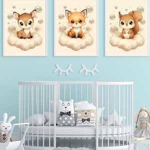 May include: Three framed wall art prints featuring a cartoon deer, a fox, and a squirrel, each sitting on a fluffy cloud surrounded by bubbles. The prints are displayed above a white crib with decorative pillows and a plush doll nearby.