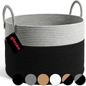Pode incluir: Um cesto de armazenamento redondo feito de corda trançada, com um design de dois tons apresentando uma seção superior cinza claro e uma seção inferior preta. Inclui duas alças laterais integradas e uma etiqueta preta com o texto branco gleckn.