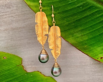 May include: Gold leaf earrings with a dark green pearl drop. The earrings are shaped like a feather.