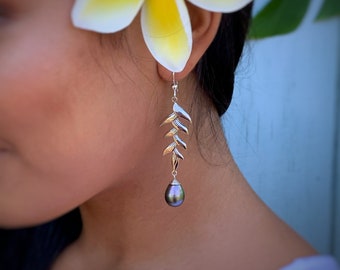 May include: Silver dangle earrings with a black pearl drop and a leaf design.