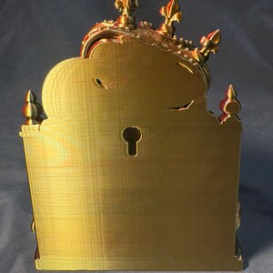 Rear view of King of the Coop in gold-toned silk PLA, showing the flat back panel, built-in keyhole-style hanging slot and decorative crown tips. Mounting hardware is not included.
