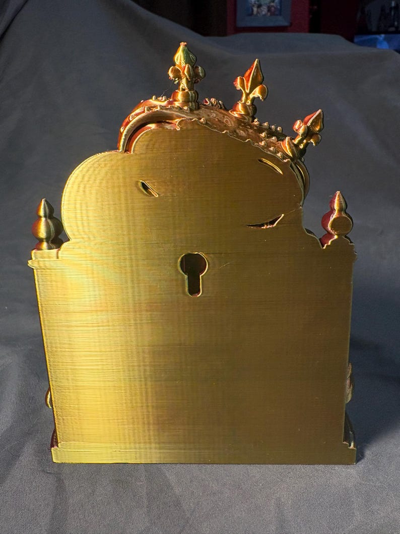 Rear view of King of the Coop in gold-toned silk PLA, showing the flat back panel, built-in keyhole-style hanging slot and decorative crown tips. Mounting hardware is not included.