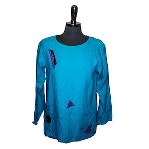 May include: A teal blue long-sleeved shirt with purple and black geometric designs.