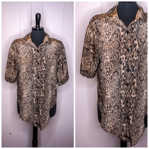 Puede incluir: Una camisa de manga corta con botones y estampado de piel de serpiente en tonos marrones y negros.