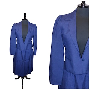 May include: A blue skirt suit with a cropped jacket and a skirt that hits just above the knee. The jacket has a single button closure and a notched collar. The skirt has a slight A-line shape.