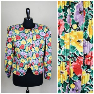 Könnte beinhalten: Eine Jacke mit Blumenmuster und Knopfleiste. Die Jacke hat einen schwarzen Hintergrund mit gelben, roten und violetten Blumen.