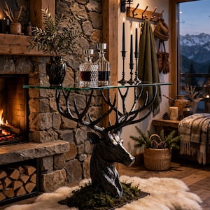 May include: A console table featuring a clear glass top supported by a dark, sculpted deer head base with branching antlers. The base is mounted on a rectangular platform covered in green moss, creating a distinct focal point for the furniture.